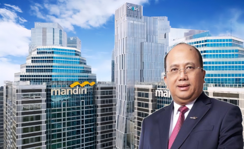 Riduan mengenakan setelan jas berdasi merah berdiri di depan Gedung Menara Mandiri di Jakarta